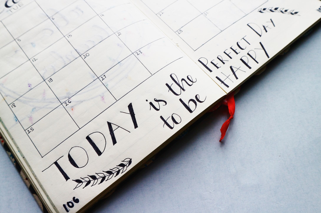Eine aufgeschlagener Terminkalender mit dem Text 'Today is the perfect day to be happy'.